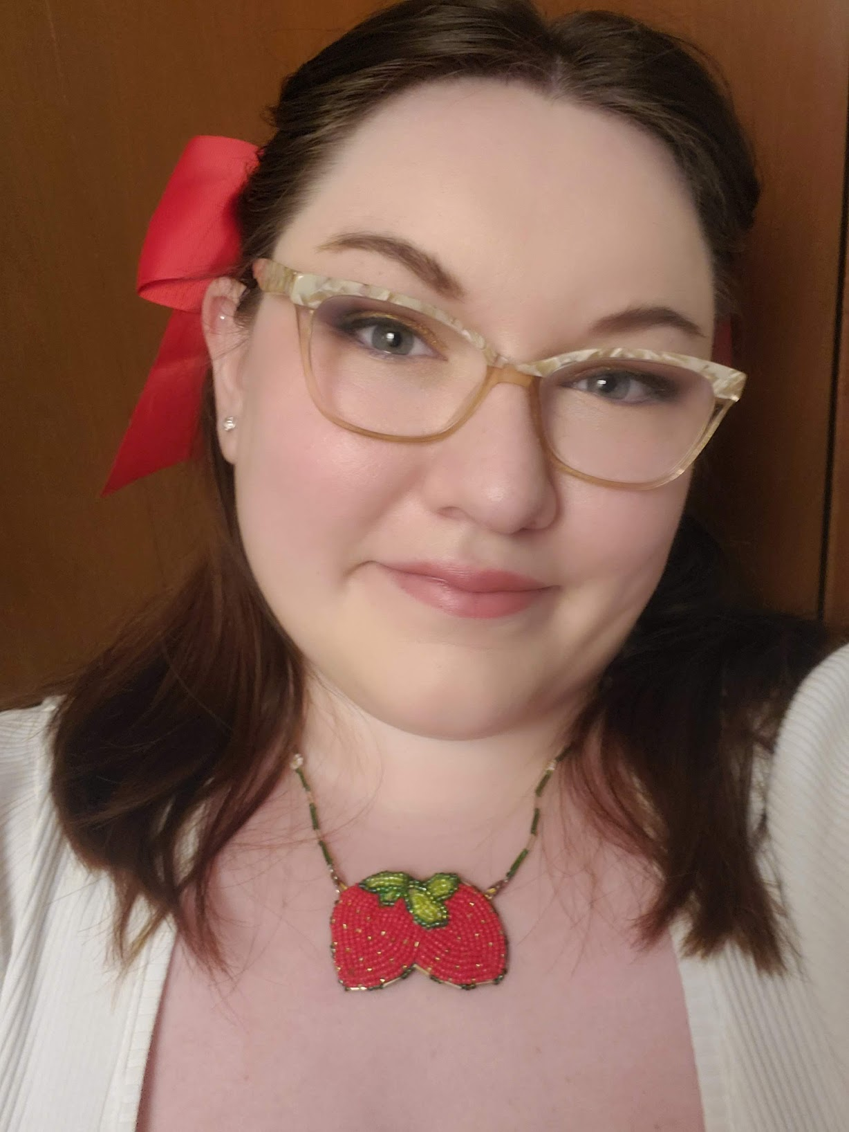 woman with gasses wearing a native american beaded necklace of two strawberries and a red bow in her hair