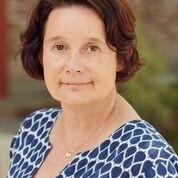 Caucasian woman with short dark hair and a blue and white patterned blouse