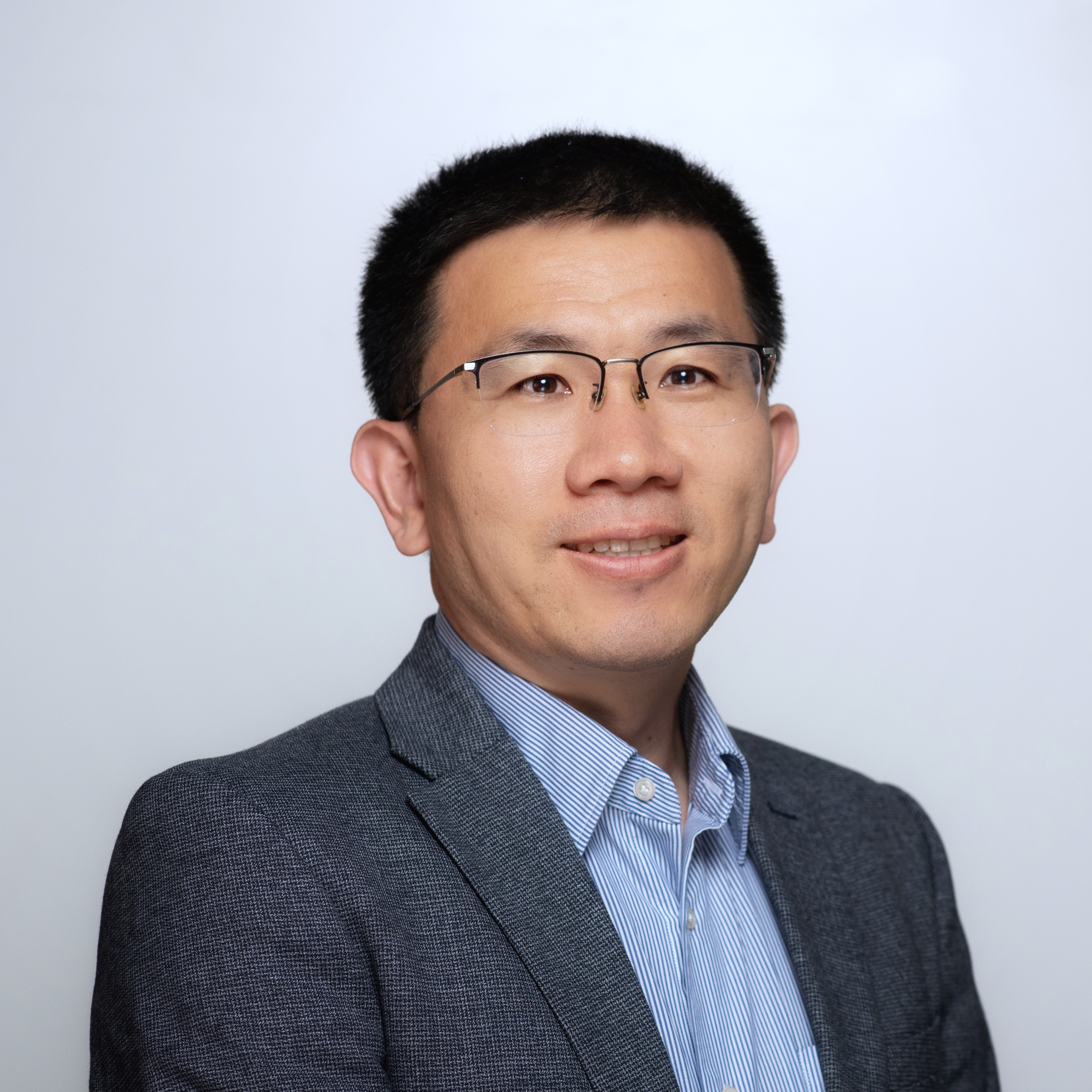 Jason Hu - Man with short, dark hair, glasses and a slight smile.  Wearing a blue button down and a grey suit jacket.