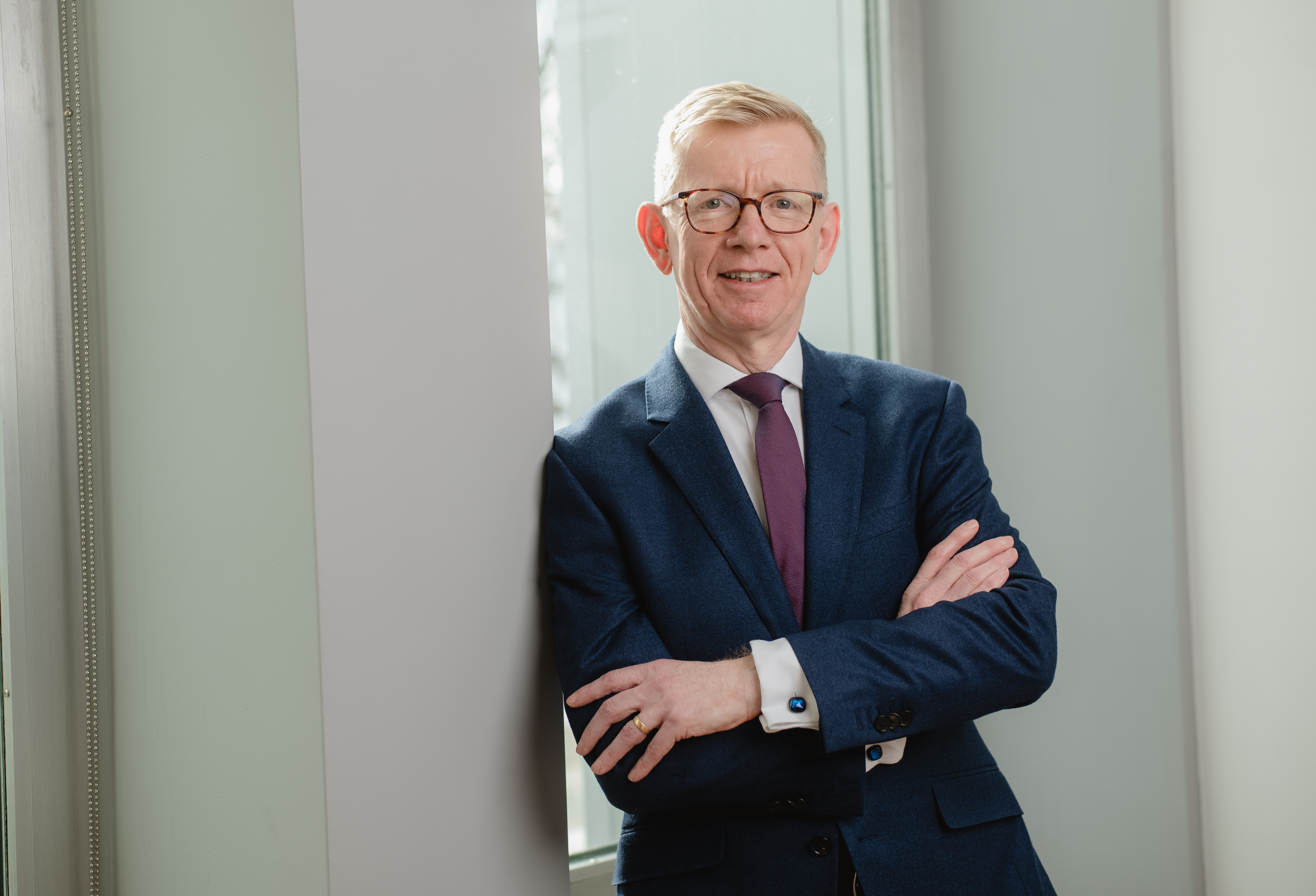 Keith Webster of Carnegie Mellon University, smiling and standing with arms crossed in a suit and purple tie.