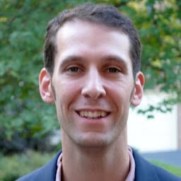 Smiling caucasian man with short hair against an outdoor backdrop