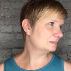 Side profile of a woman with short blonde hair, wearing a strapless blue blouse
