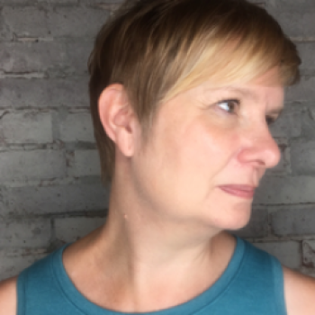 Side profile of a woman with short blonde hair, wearing a strapless blue blouse