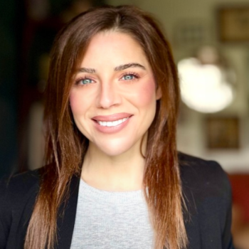 Photo of smiling woman with long har and wearing a blazer. 